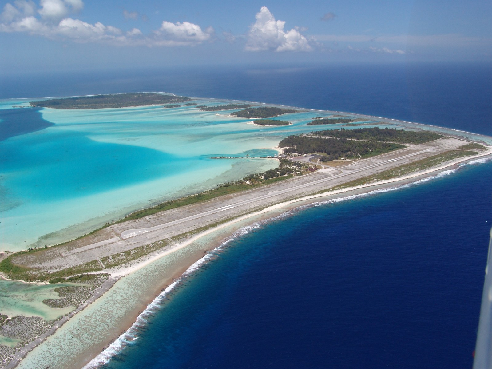 Aerial view of Bora Bora Airport’s runway on Motu Mute, surrounded by turquoise lagoon and deep blue ocean.