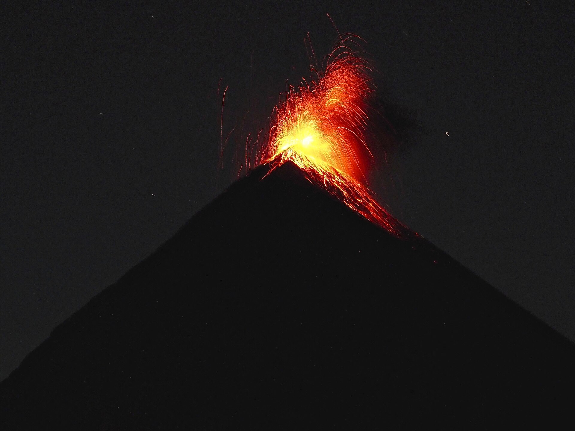 Glowing volcanic material erupting from Volcán de Fuego against the night sky