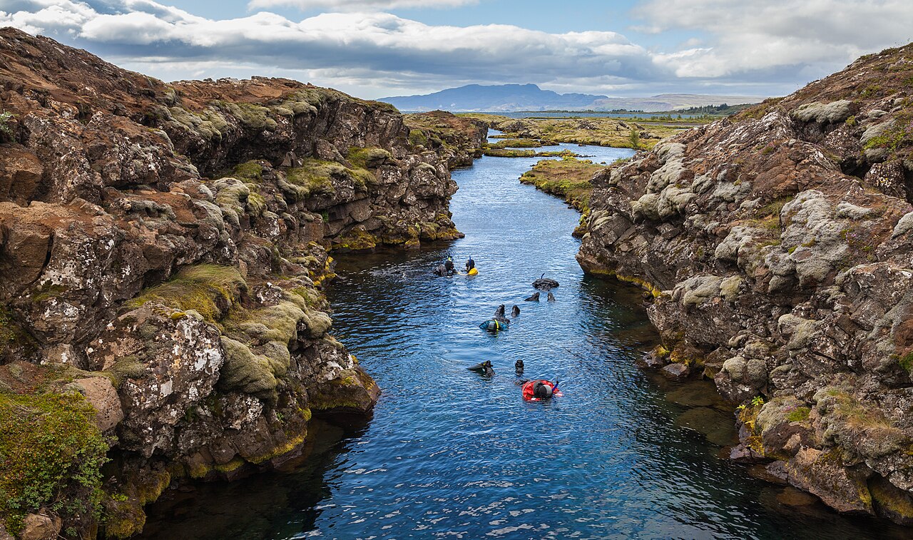 Snorkelers floating between the rocky walls of Silfra in Þingvellir