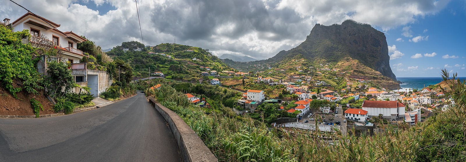 Porto da Cruz's red-roofed coastal village below Penha de Águia, with the Atlantic on the right.